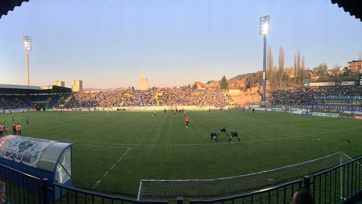 Pun stadion Grbavica u Sarajevu u predvečerje, s navijačima Željezničara na tribinama i igračima na zagrijavanju