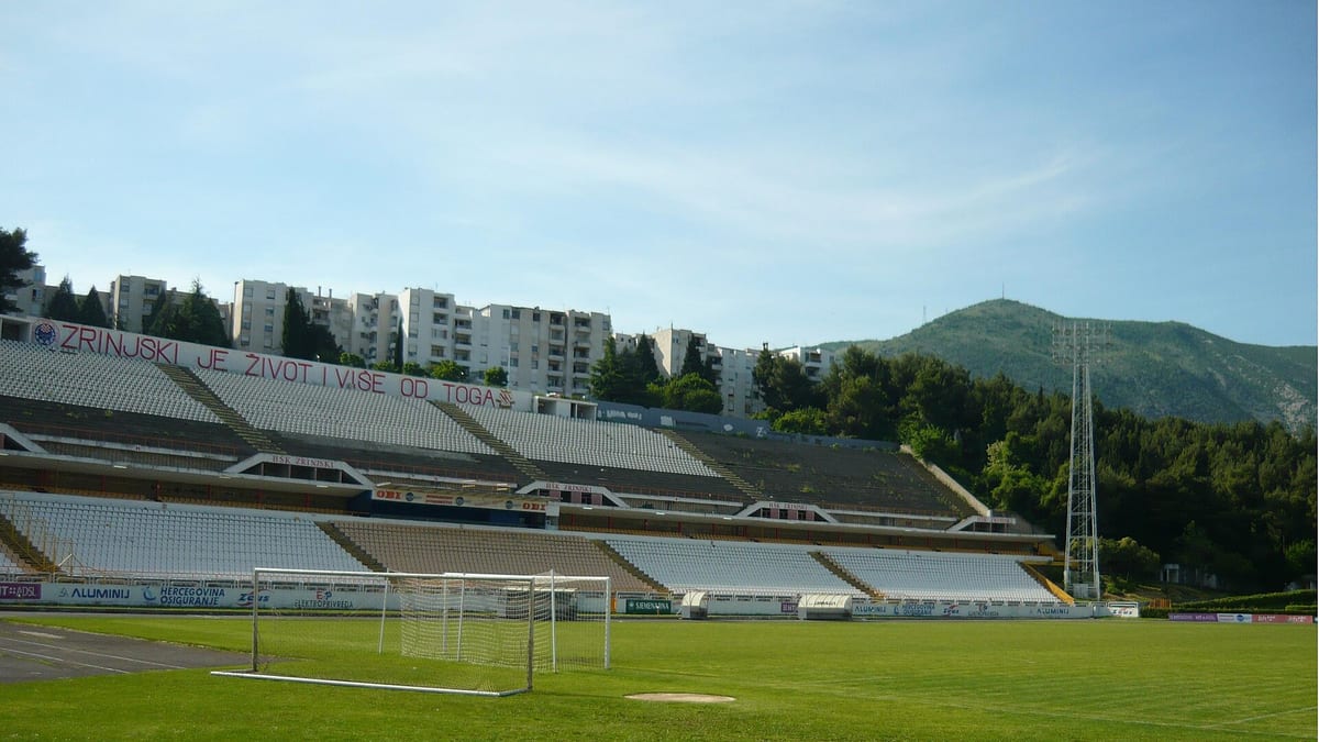 Stadion pod Bijelim Brijegom u Mostaru, glavna tribina s bijelim sjedalima i natpisom Zrinjski je život i više od toga, u pozadini planina