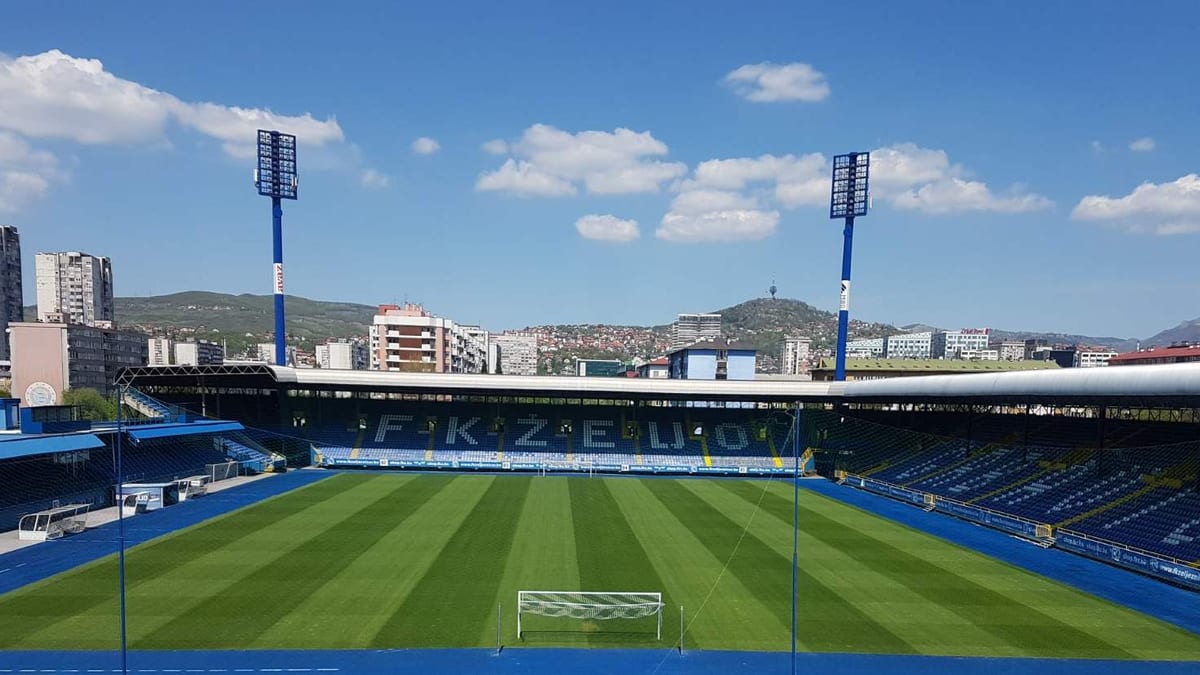Stadion Grbavica u Sarajevu u aprilu 2020, pogled na zeleni teren, gol i plavu tribinu s natpisom FK ŽELJO
